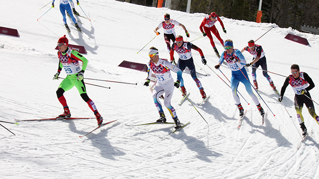 Kilpaurheilijat hiihtävät murtomaahiihtoa.
